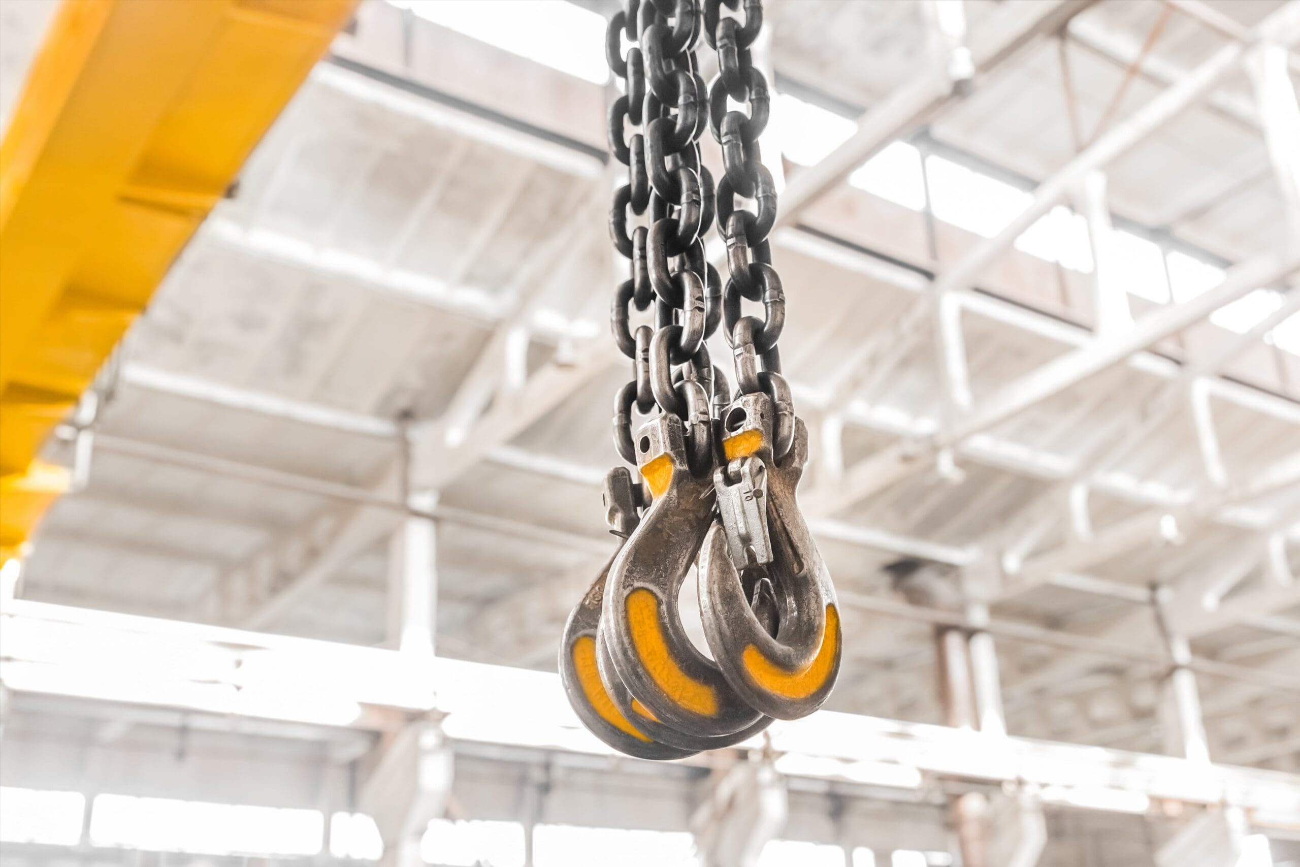 A close up image of hooks hanging from a crane in a factory