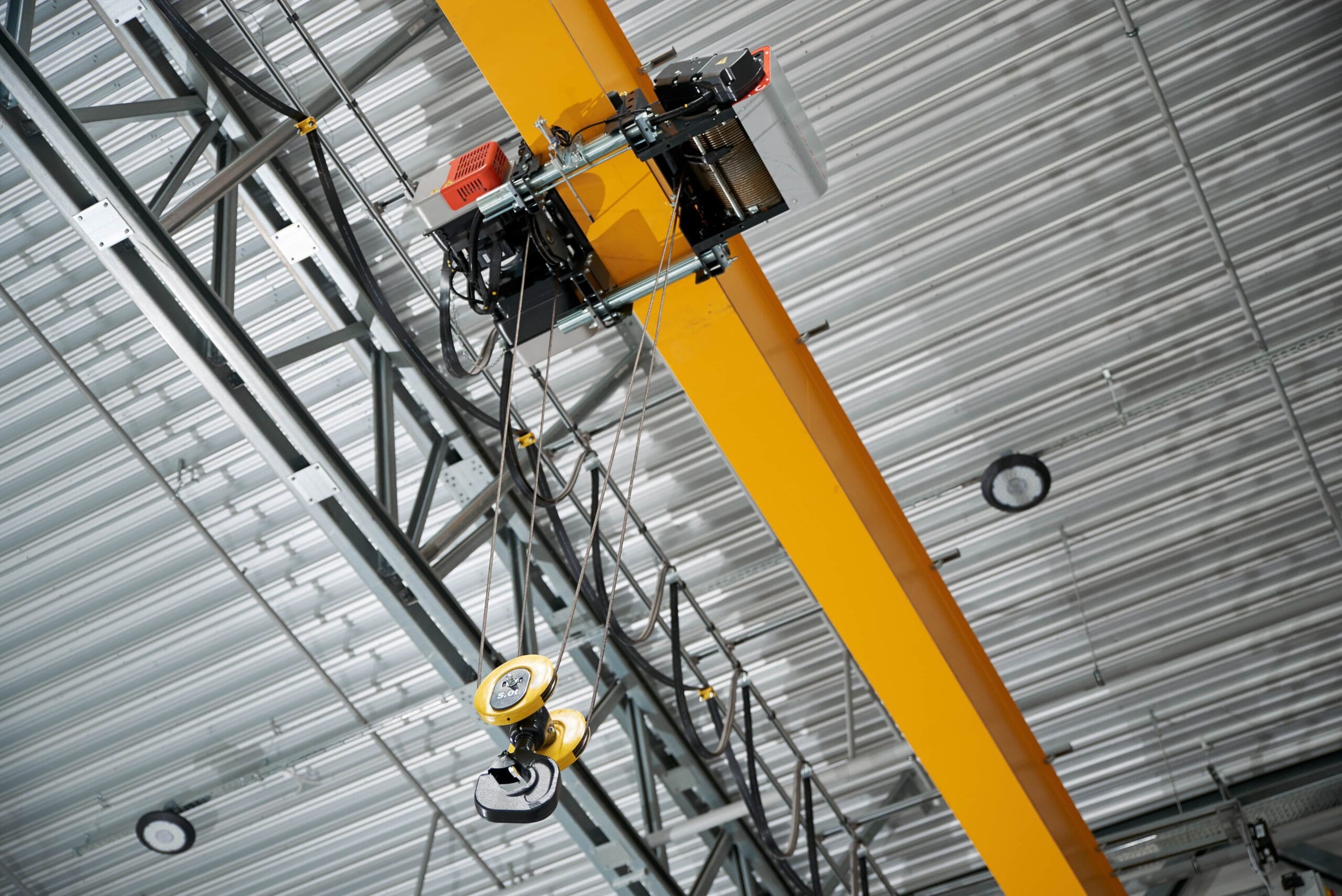 A crane and hook hanging from the ceiling of a factory